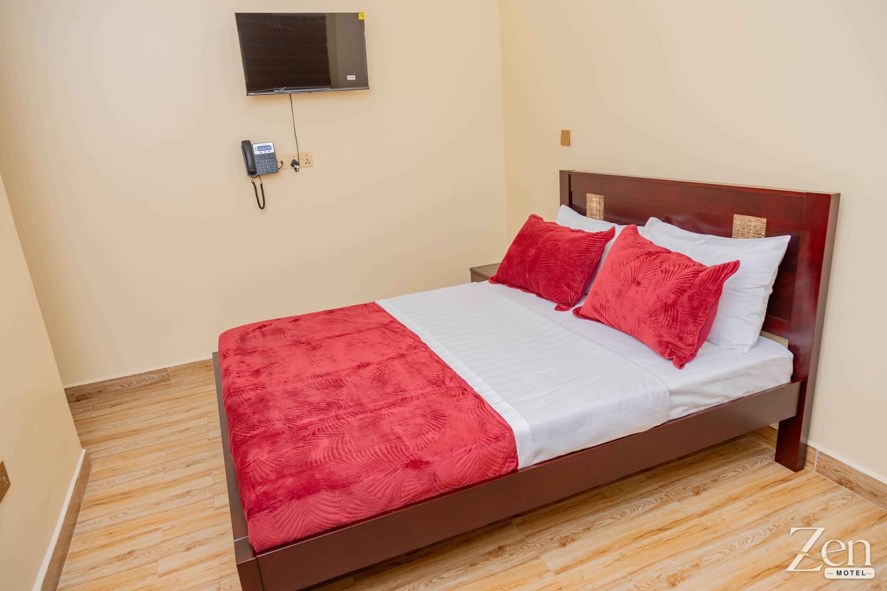 Double bed with a wall-mounted TV and telephone