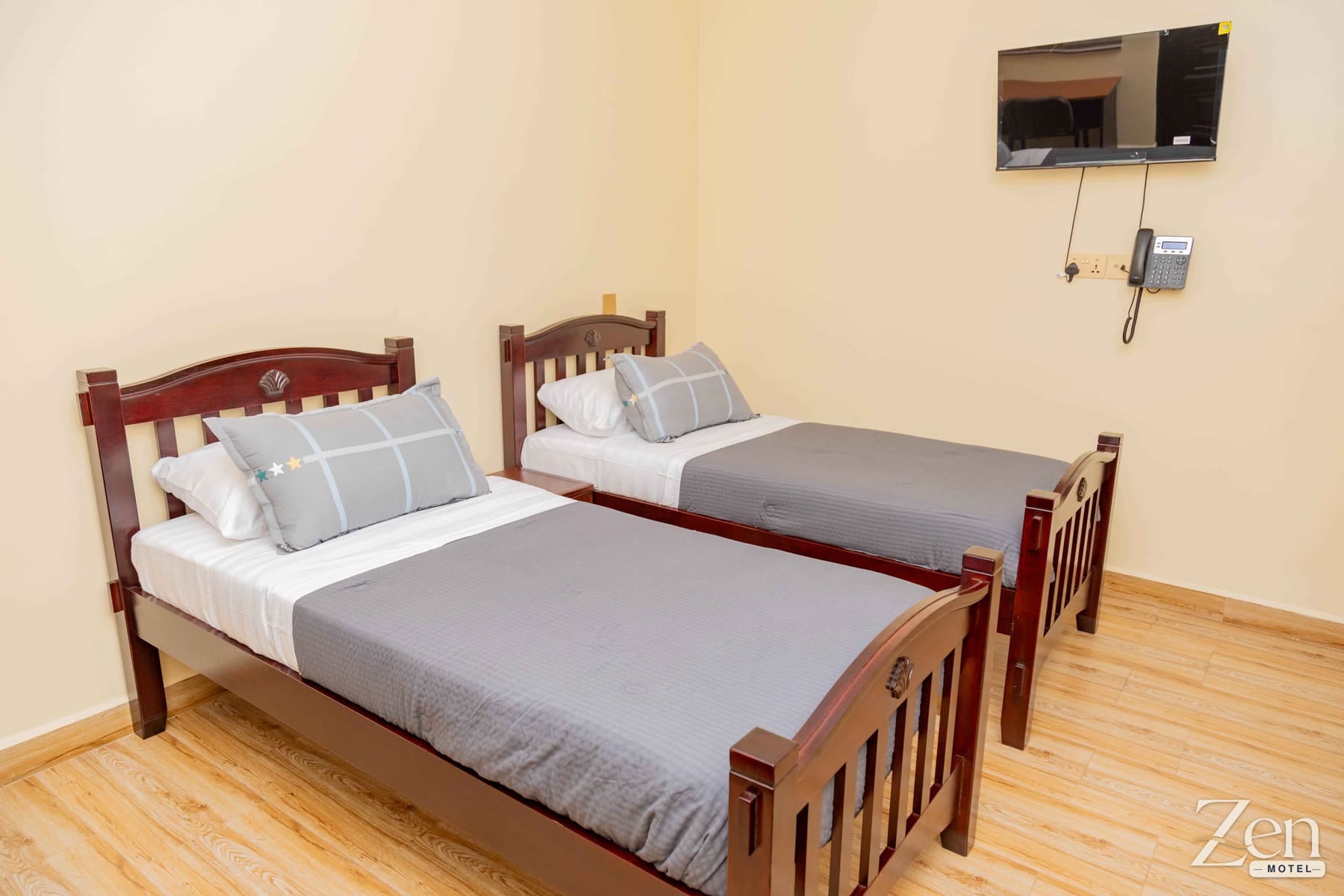 Two single beds with a wall-mounted TV and telephone